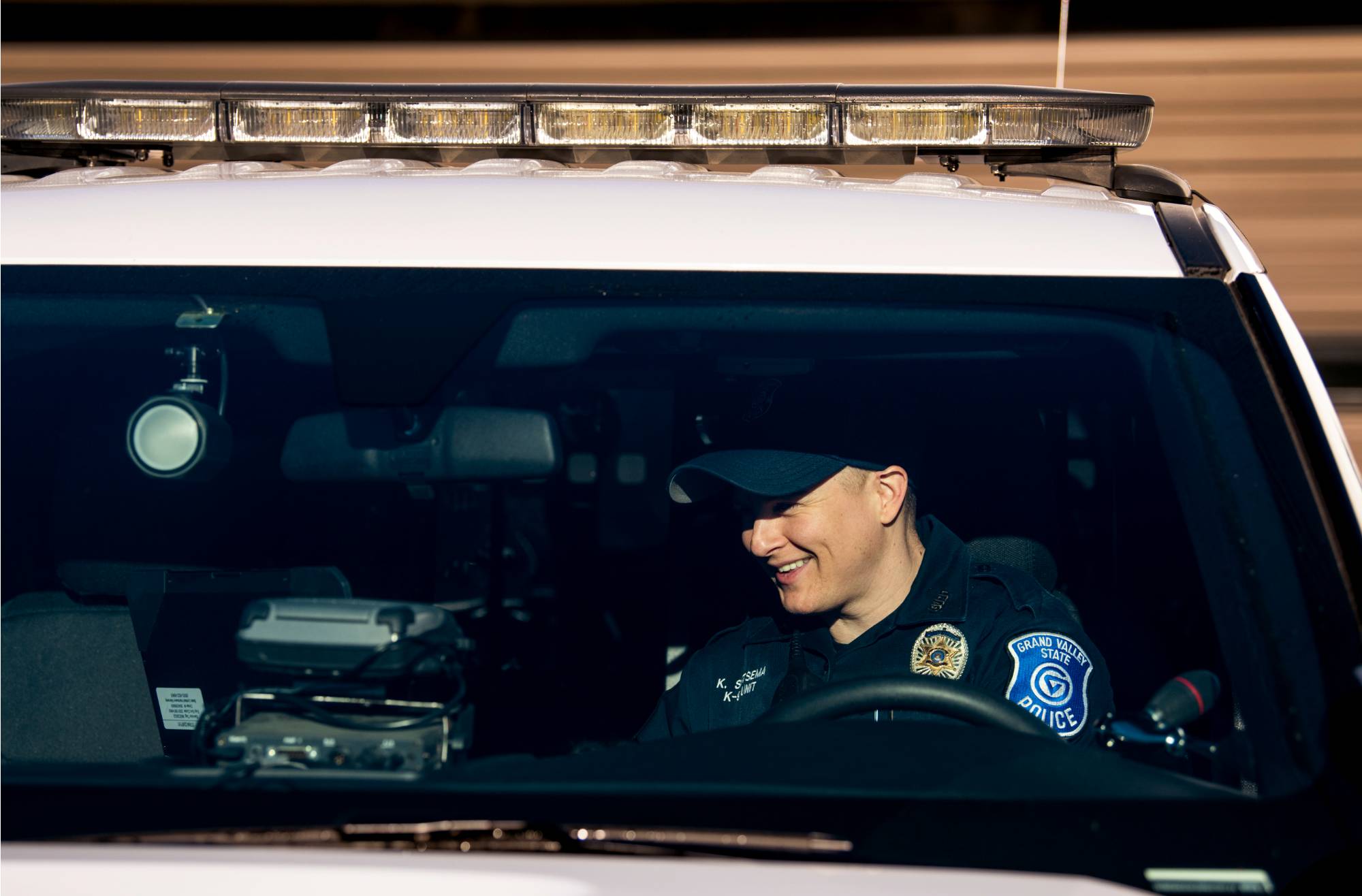 Police officer in front of a cruiser smiling